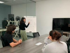 Marketers sitting around a long conference table surrounded by glass walls while talking about marketing.